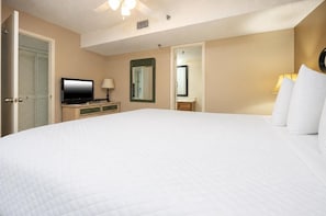 Een hotelkamer met een groot bed, een televisie, een spiegel en een bureau met een lamp.