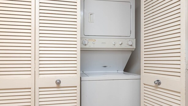 A laundry room with a washing machine and dryer, enclosed by white louvered doors. - Phoenix Iii 3075 1 Bedroom Condo (Orange Beach)