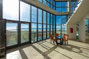 Ein geräumiges Zimmer mit großen, raumhohen Fenstern und Blick auf den Strand und das Meer.