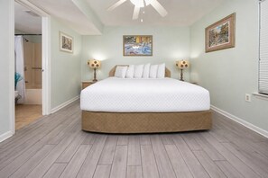 Ein Schlafzimmer mit einem großen Bett, zwei Nachttischen, einem Deckenventilator und zwei Wandleuchten.