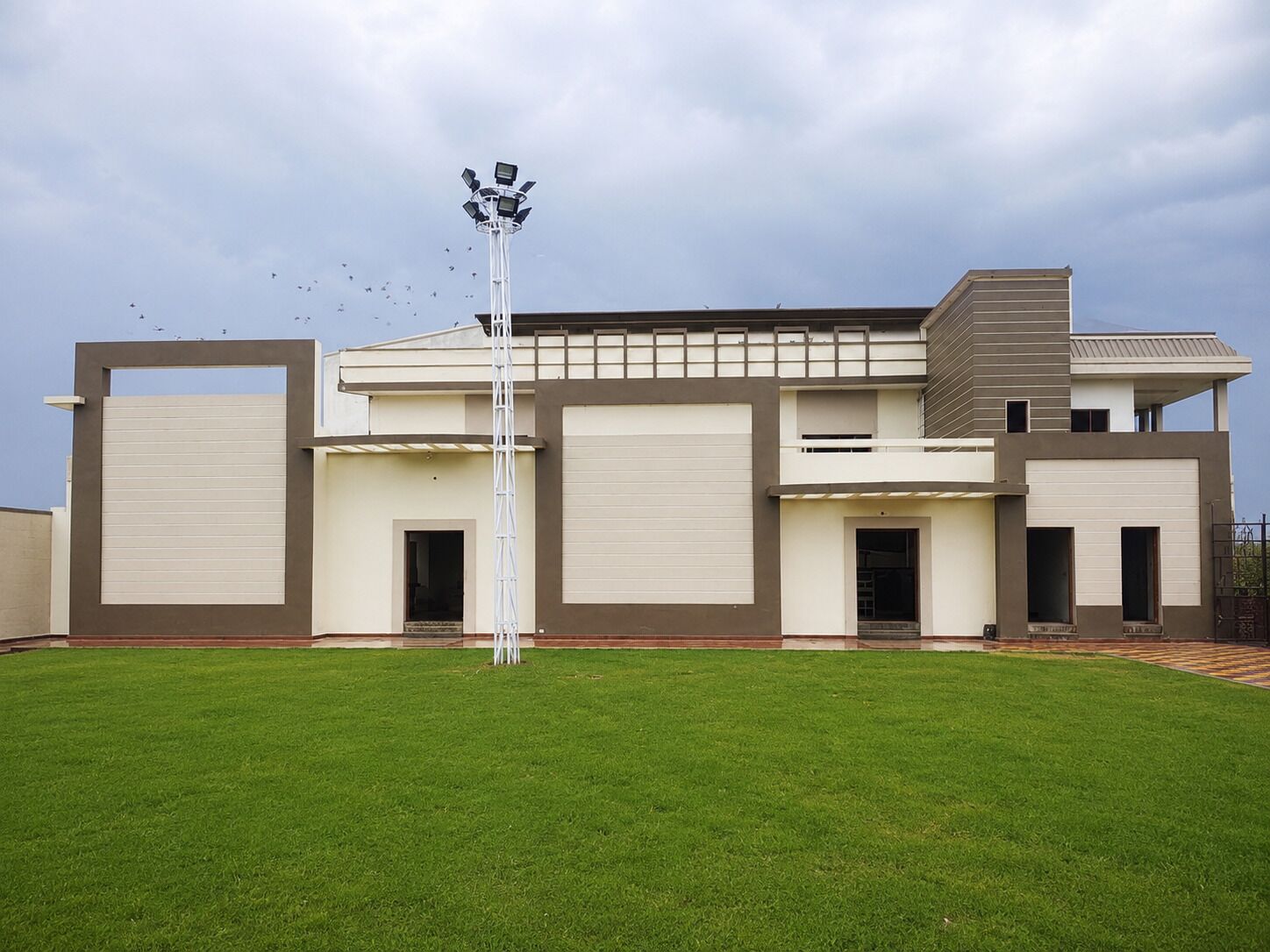 Un bâtiment moderne à deux étages, doté d’un toit plat, de grandes portes de garage et d’une pelouse bien entretenue.