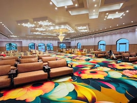 A large conference room with rows of chairs, a colorful floral carpet, and a chandelier.