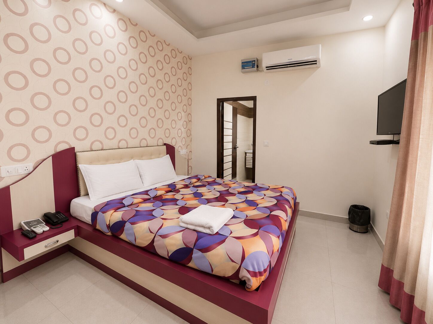 A hotel room with a bed, bedside table, and a television.