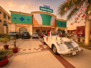 A hotel entrance with a vintage car decorated with flowers, parked in front.