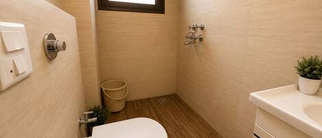 A bathroom with a toilet, a shower, and a sink.