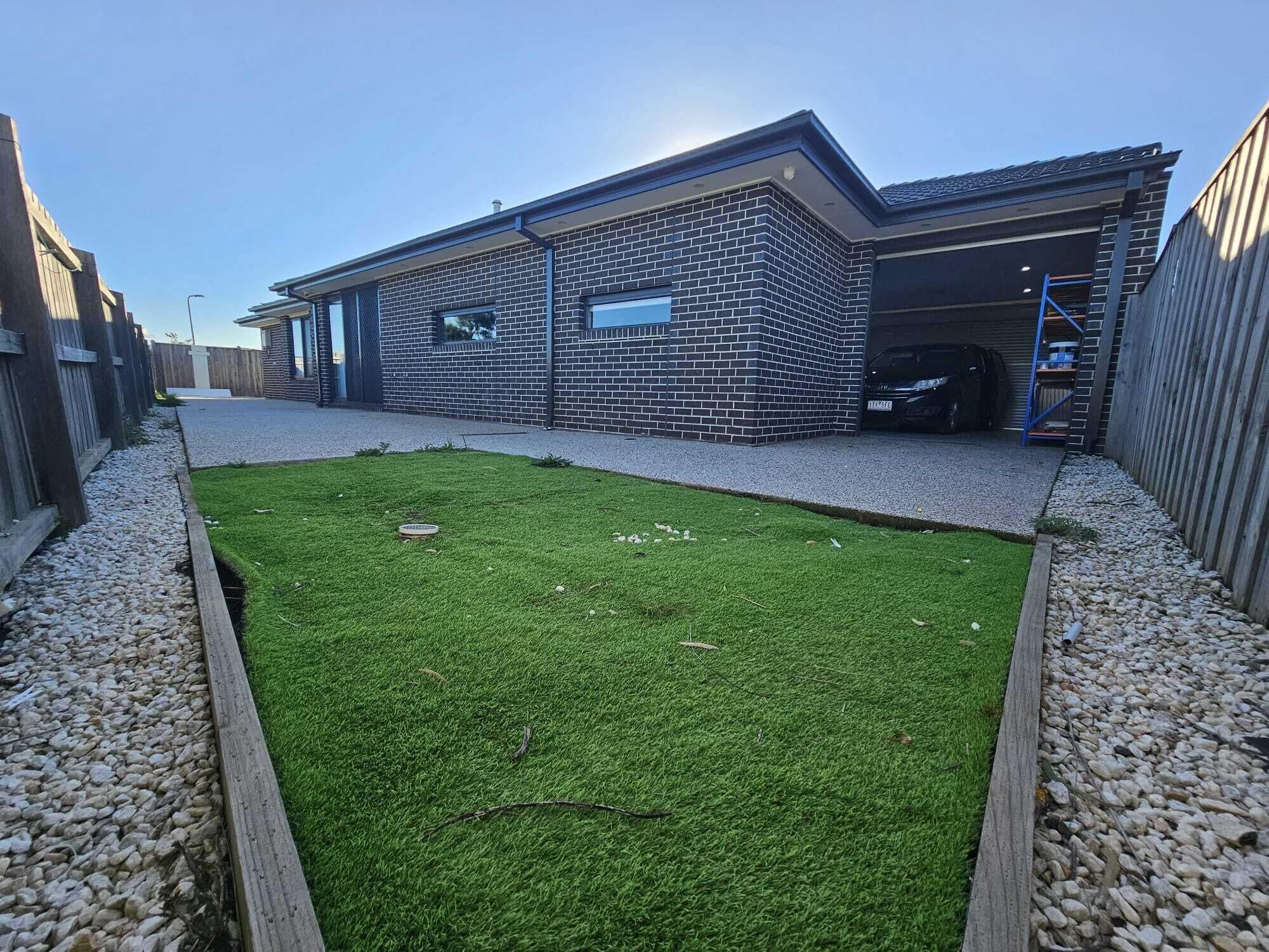 A modern building with a brick facade, a garage, and a well-maintained lawn.