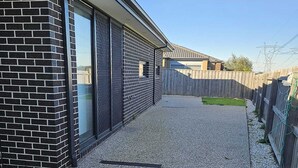 En bostadsfastighet med en grusuppfart, ett trästaket och en fasad av tegel.