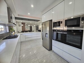 Eine moderne Küche mit Edelstahlgeräten, einer zentralen Kochinsel und einem großen Backofen.
