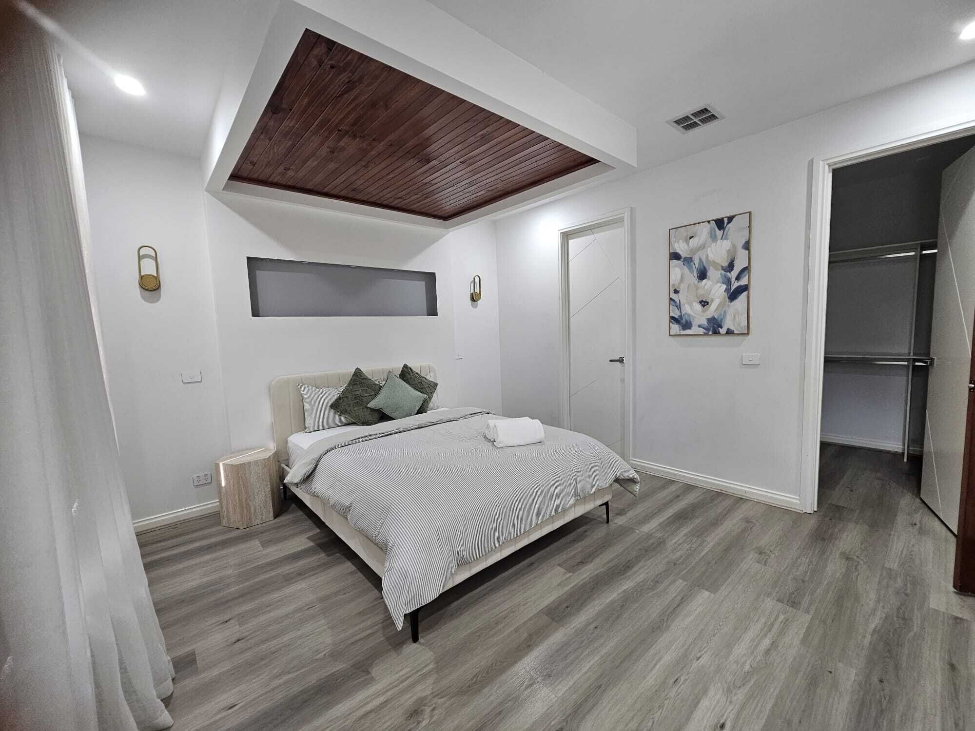 A bedroom with a bed, a wooden ceiling, a wardrobe, and a painting.