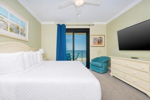 A hotel room with a large bed, a TV, a dresser, a chair, and a balcony with a view. - Phoenix Vii 71108 3 Bedroom Condo (Orange Beach)