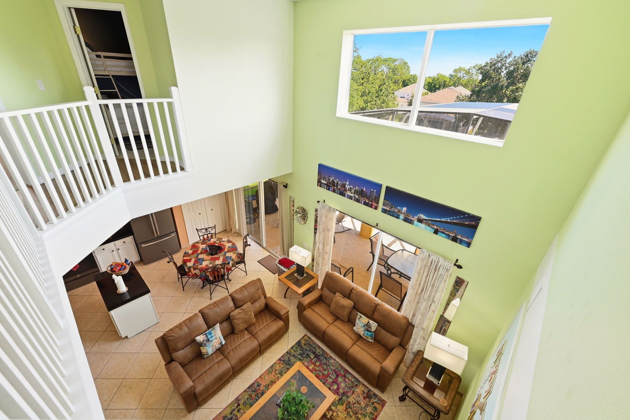 Een ruime woonkamer met een hoge plafond, een balkon en een eethoek.