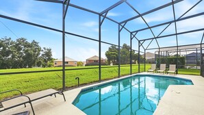 Une piscine avec une structure en métal et une zone herbeuse en arrière-plan.
