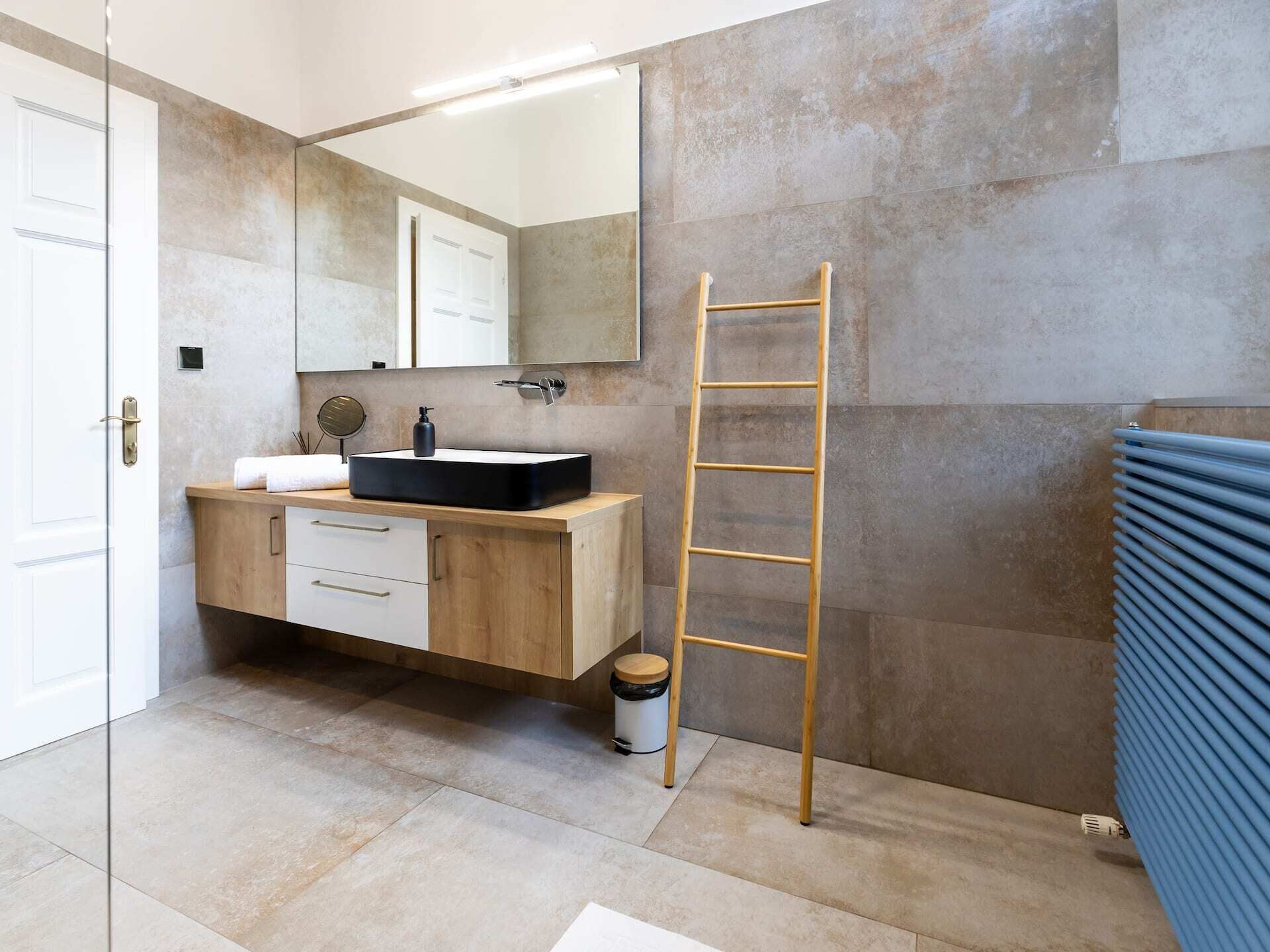 Un baño moderno con tocador de madera, un espejo, un lavabo y un perchero para toallas.