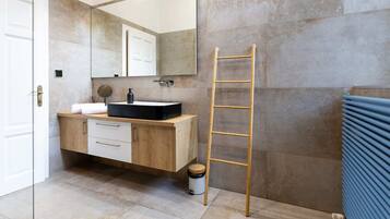 Un baño moderno con tocador de madera, un espejo, un lavabo y un perchero para toallas.