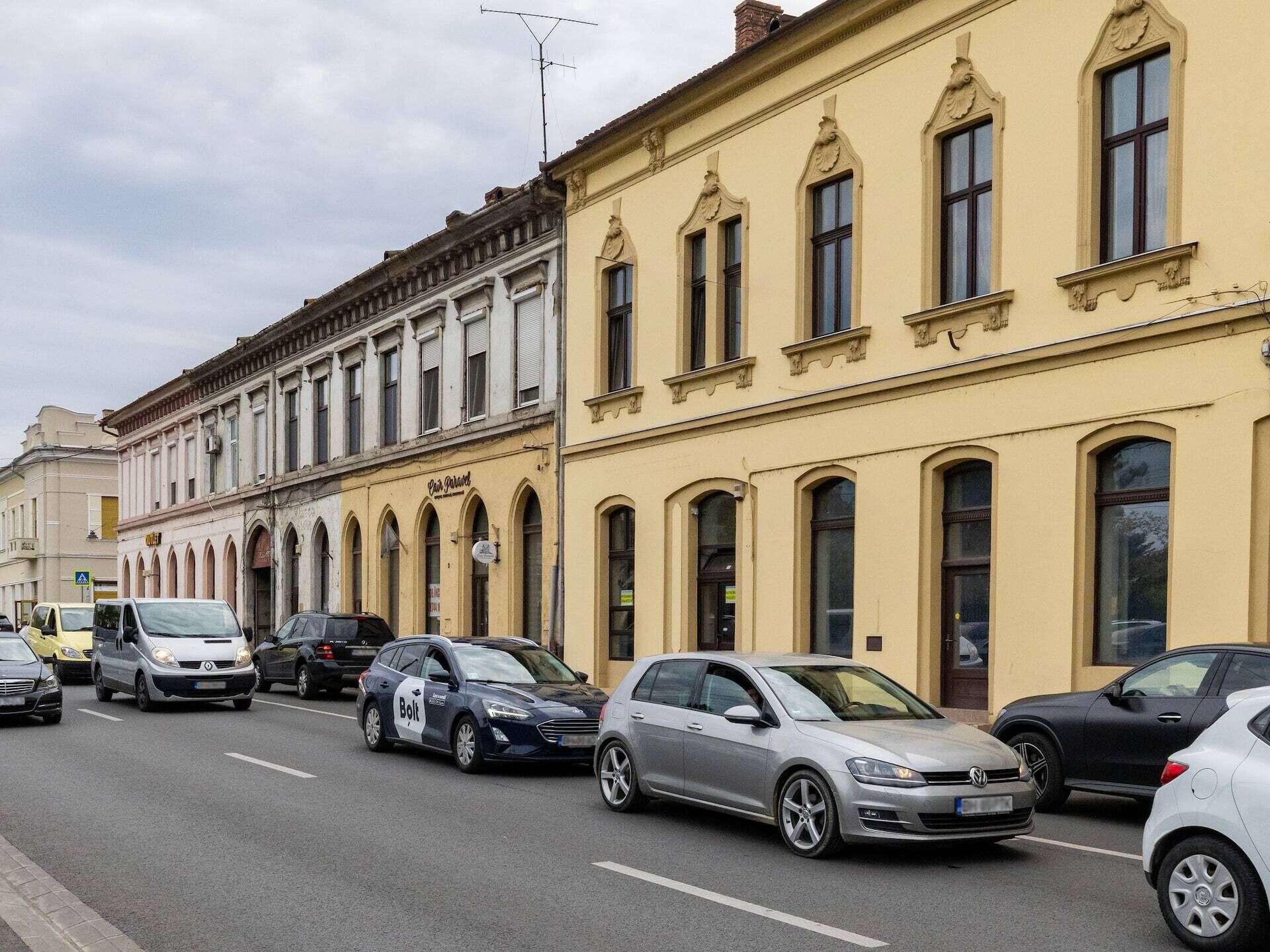 Une rue bordée de voitures garées et d’immeubles historiques à l’architecture classique.
