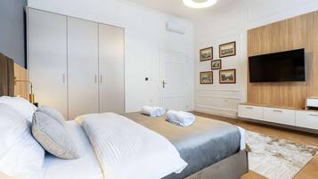 A modern bedroom with a bed, wardrobe, and a TV on the wall.