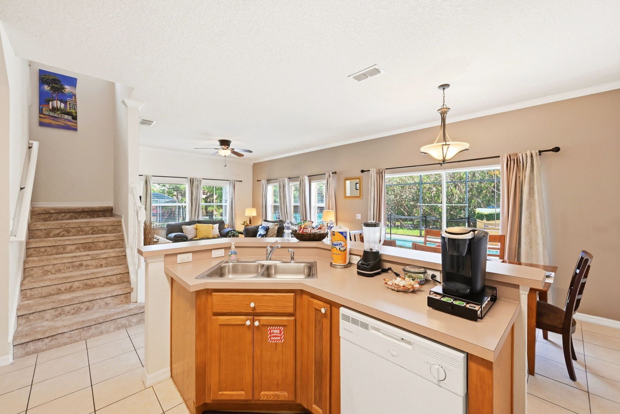 A kitchen with a built-in dishwasher, a coffee maker, and a dining area with a table and chairs.