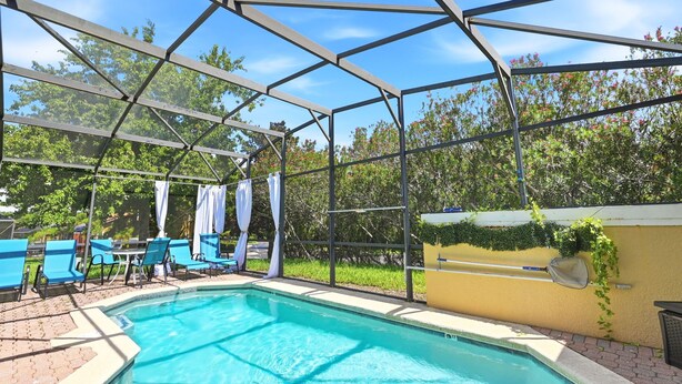 Uma piscina com área coberta, cadeiras de descanso azuis e uma parede amarela.