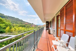 Ein Balkon mit Blick auf eine hügelige Landschaft, ein Tisch mit Stühlen und ein Gebäude mit Holzhörnern.