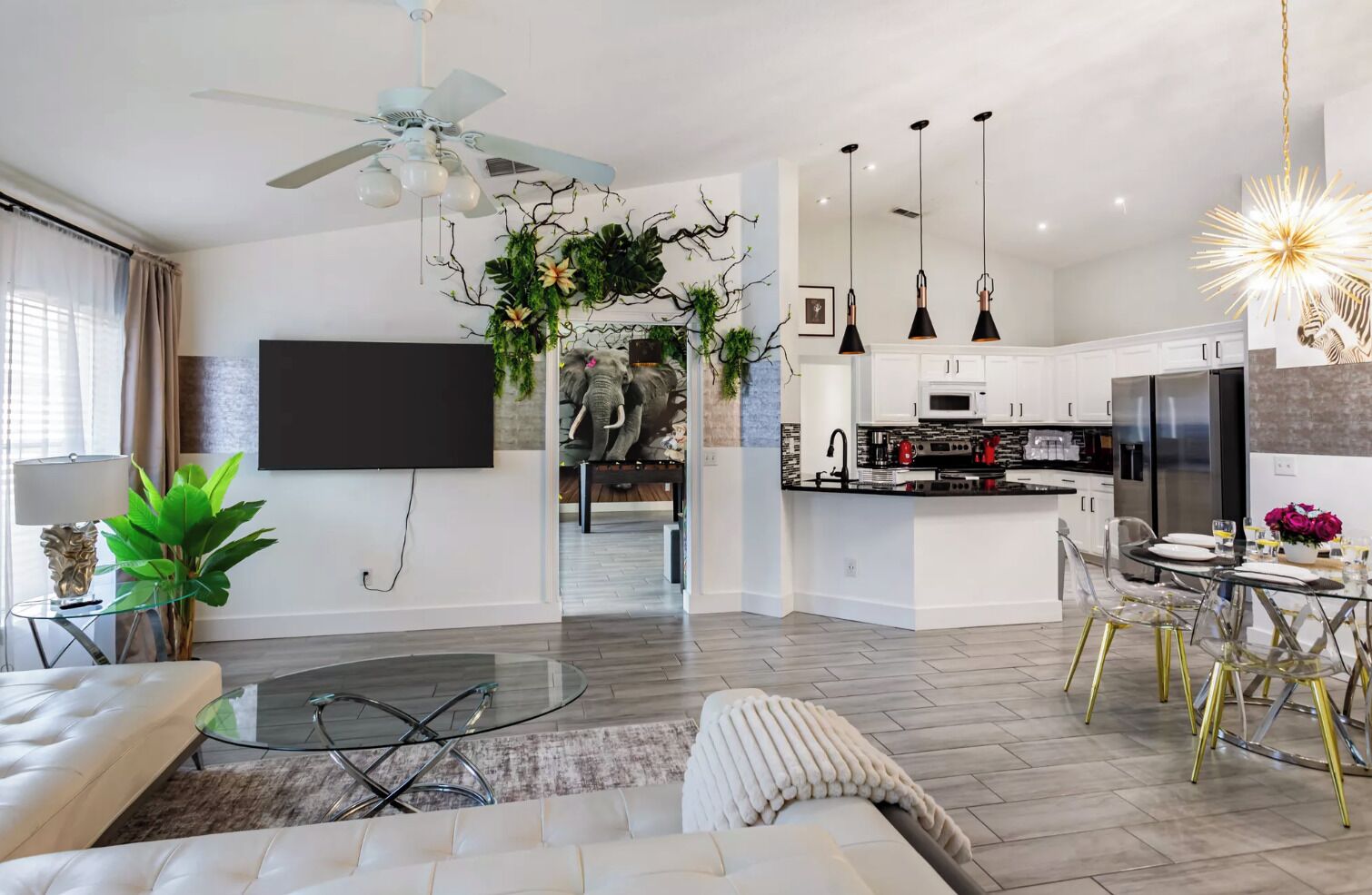 A modern living room with a sofa, a glass coffee table, a TV, and a ceiling fan.