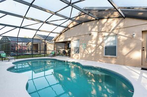 A swimming pool with a glass enclosure, a covered patio area, and a door to the right. - 3BR Tropical Oasis w/ Pool & Foosball near Disney (Kissimmee)