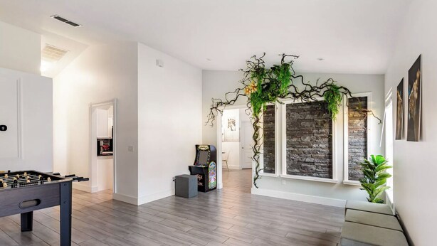 Een modern interieur met een tafelvoetbaltafel, een spelconsole en een muur met een stenen structuur.