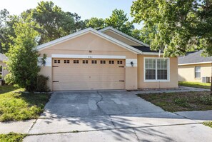 A single-story house with a garage, a front yard, and a tree. - 3BR Tropical Oasis w/ Pool & Foosball near Disney (Kissimmee)