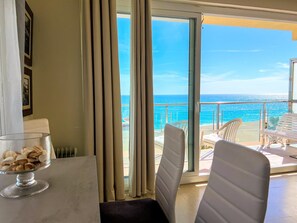Ein Zimmer mit Blick auf das Meer, ein Glastisch mit einer Dekoration und ein weißer Stuhl.