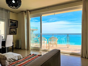Ein Hotelzimmer mit einer großen Schiebeglas-Tür, die auf einen Balkon mit Meerblick führt.