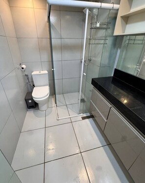Een moderne badkamer met toilet, douchecabine van glas en een zwart aanrecht.