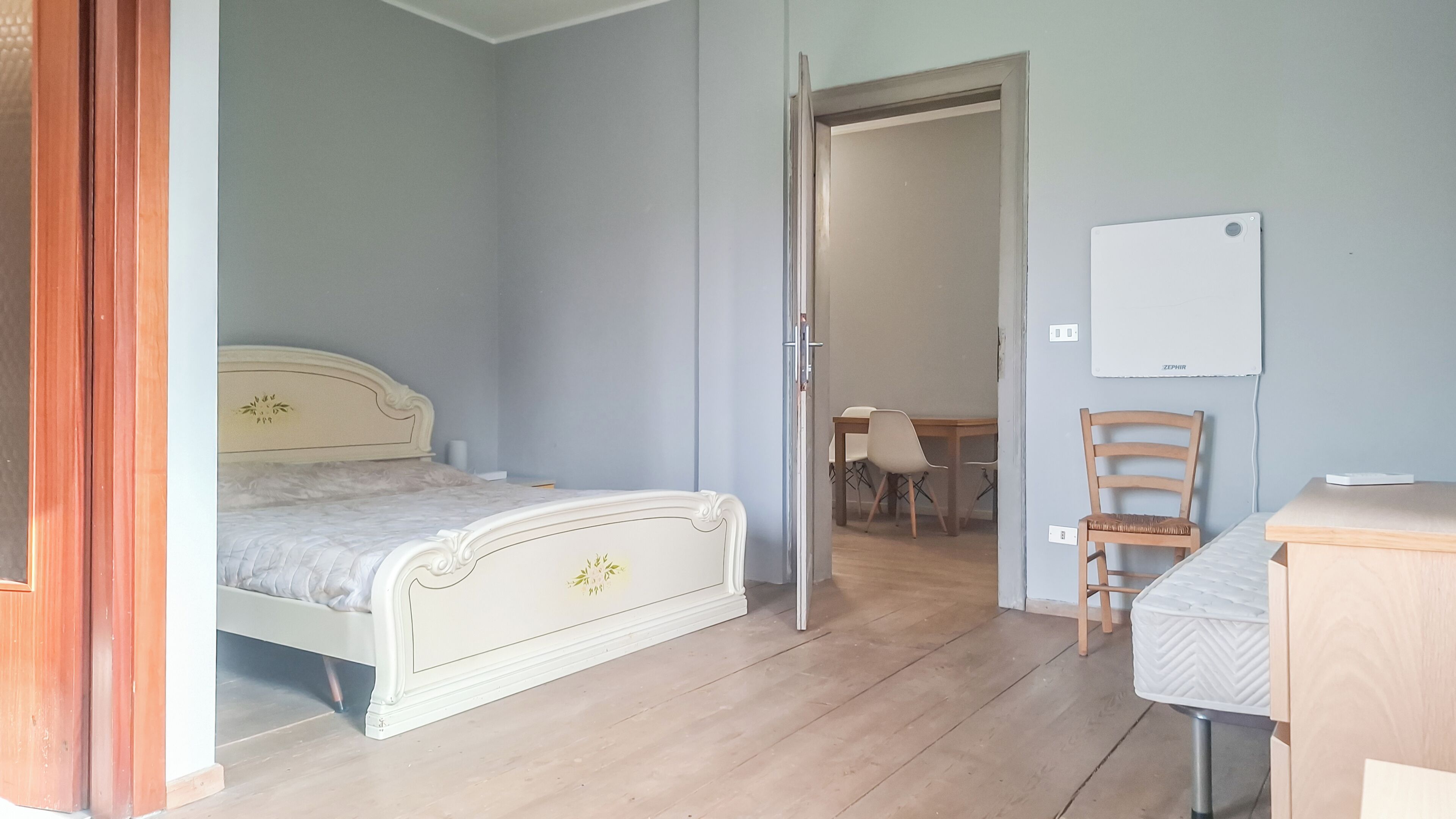Un dormitorio con una cama, una silla, un escritorio y una pizarra en la pared.