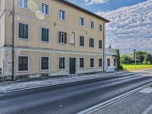A two-story building with multiple windows, a central entrance, and a street in front.