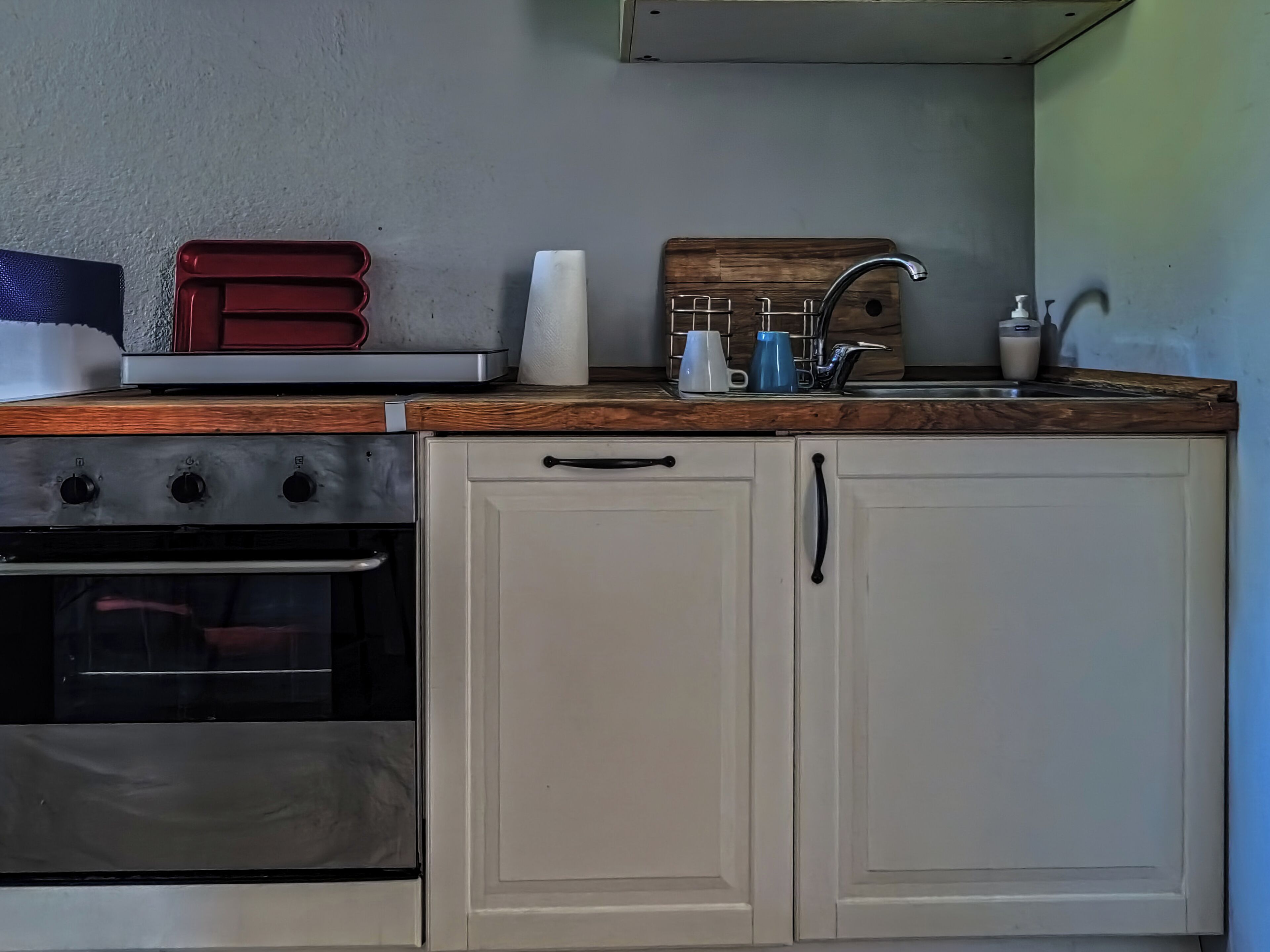 A compact kitchen with a stove, oven, sink, and wooden countertop.