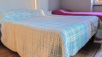 A room with two beds, one with a blue and white checkered bedspread and the other with a purple bedspread.