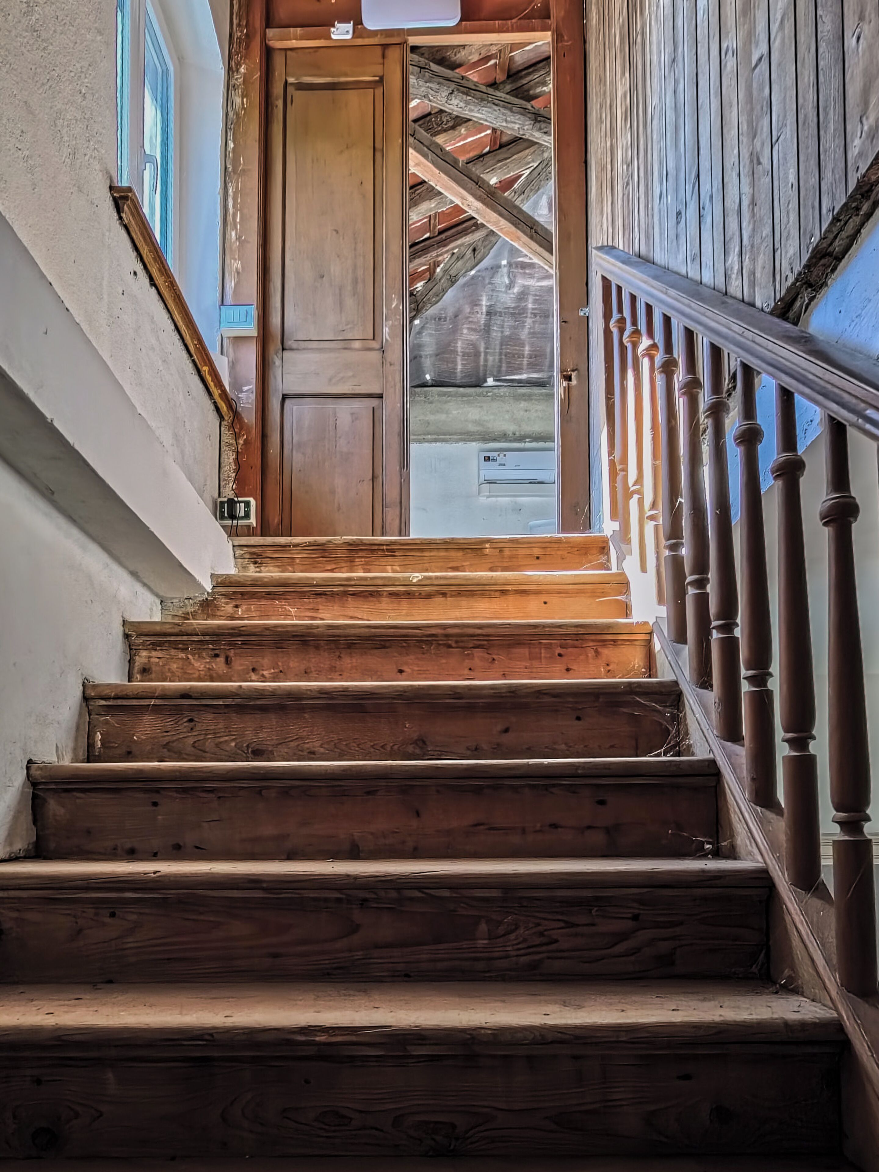 Eine Holztreppe mit Handlauf, die zu einer Tür führt.