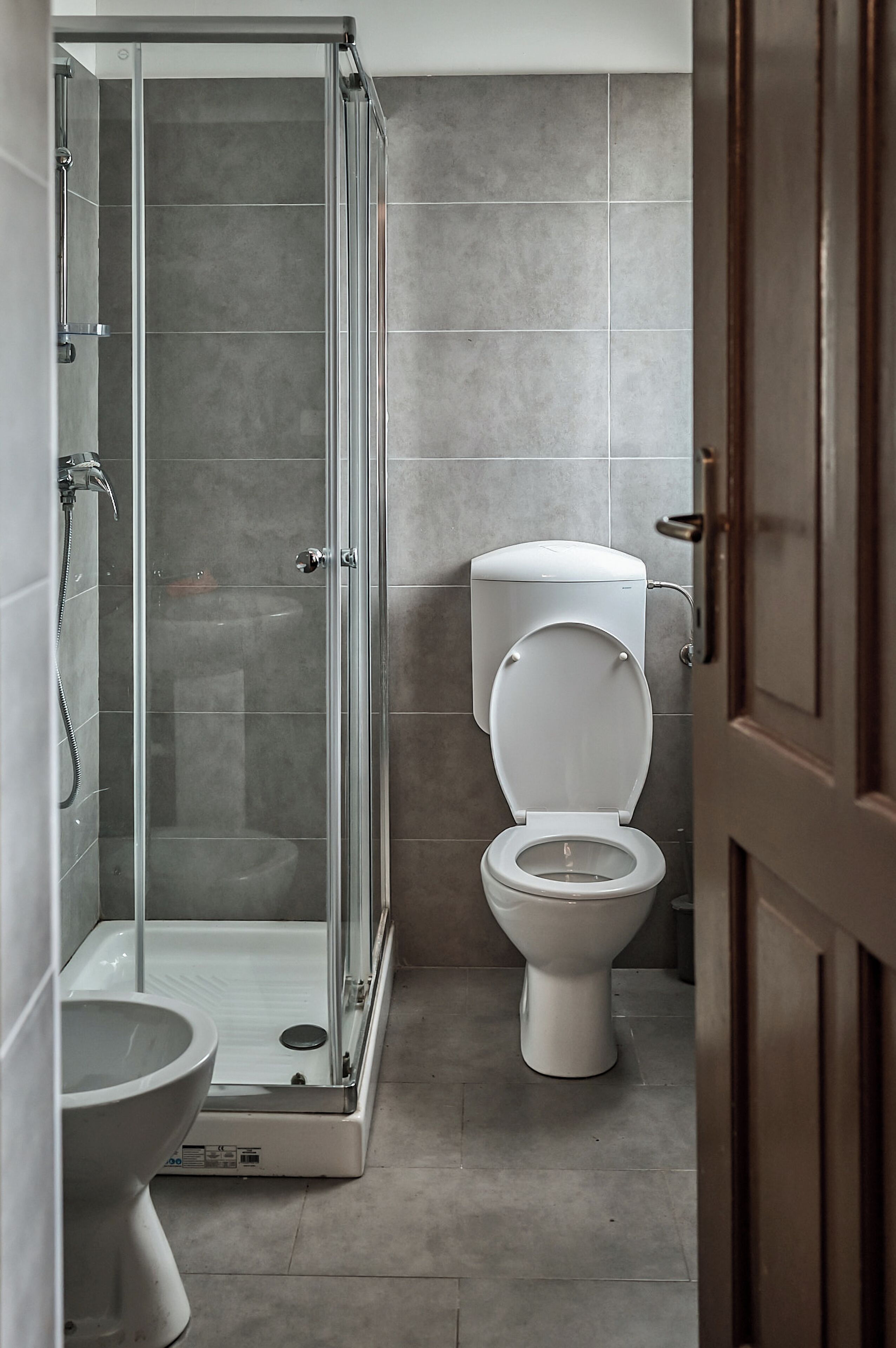 A bathroom with a glass-enclosed shower, a toilet, and a bidet.