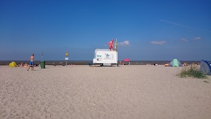 A beach with a lifeguard station, tents, and people. - Apartment 'Fewo Tenge EG Links' with Covered Terrace, Private Garden and Wi-Fi (Wangerland)