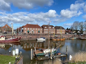 Ein Hafen mit vertäuten Booten, ein Backsteinhaus und ein klarer Himmel.