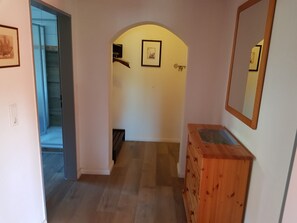 Ein Korridor mit einem Holzkasten, einem Spiegel und einem gerahmten Bild an der Wand.