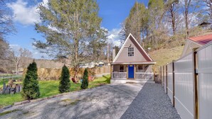 A small house with a blue door, a porch, and a gravel driveway. - Cozy Pigeon Forge Cabin Near Dollywood・Fire Pit (Pigeon Forge)
