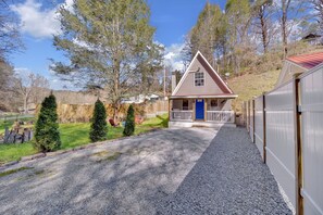 Ein kleines Haus mit einer blauen Tür, einer Veranda und einer Auffahrt mit Kies.