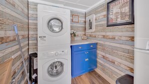 A laundry room with stacked washing machines, a blue cabinet, and a framed picture on the wall. - Cozy Pigeon Forge Cabin Near Dollywood・Fire Pit (Pigeon Forge)