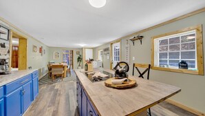 Eine Küche mit blauen Schränken, einer Holz Arbeitsplatte und einem Essbereich mit Tisch und Stühlen.