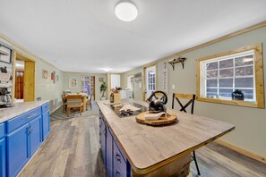A kitchen with blue cabinets, a wooden countertop, and a dining area with a table and chairs. - Pigeon Forge Single-Level Retreat Near Dollywood (Pigeon Forge)