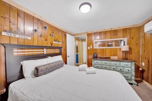A bedroom with a wooden headboard, a bed with white bedding, a dresser with drawers, and a mirror above the dresser. - Pigeon Forge Single-Level Retreat Near Dollywood (Pigeon Forge)
