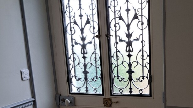 A door with decorative metal bars and a patterned floor. -  grande propriété close (Polisot)