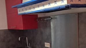 A kitchen with a stainless steel sink, red cabinets, and a blue and white backsplash. -  grande propriété close (Polisot)