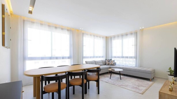Un salon moderne comprenant une table à manger, des chaises, un canapé et un téléviseur.