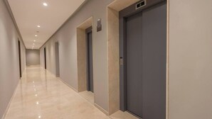 Un couloir doté d’un sol poli, de portes et d’un écran numérique placé au-dessus de l’une des portes.