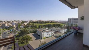 Un balcon offrant une vue sur le paysage urbain, avec des bâtiments et un parc.